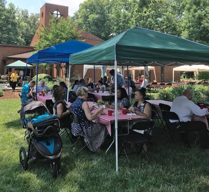 Adults and children eat at tables under tents in the yard at the gayton kirk in henrico va