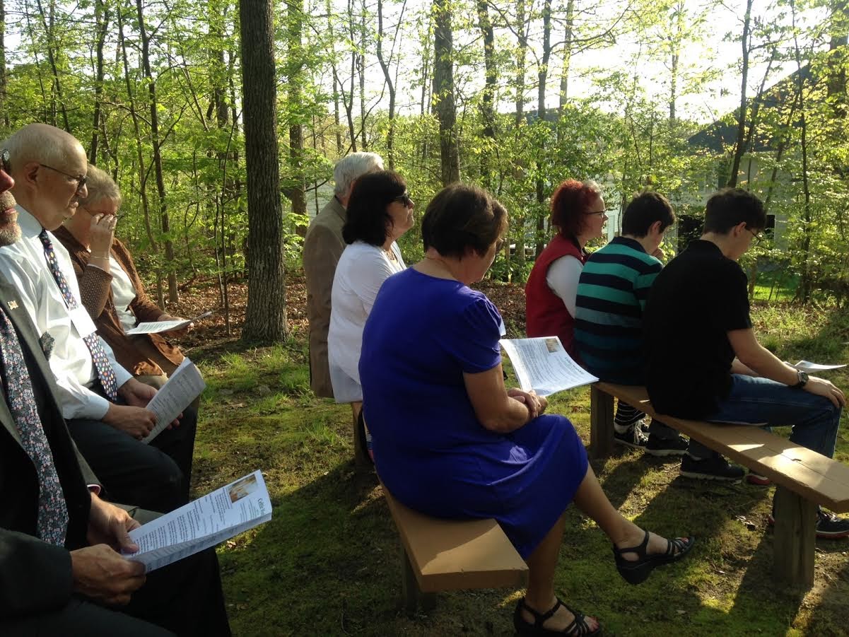 people sit on benches in the woods at the gayton kirk presbyterian church for outdoor celtic worship service